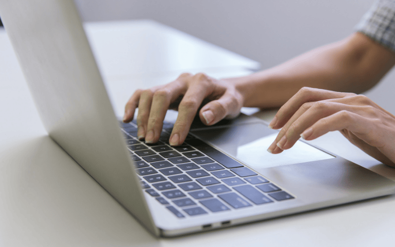 Personne utilisant un ordinateur portable pour illustrer des conseils de création de site Internet destiné aux artisans du bâtiment.